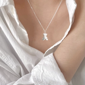 Detail of 925 silver teddy bear pendant with heart accent on a model's neck