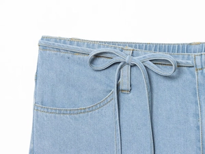 Detail der hellblauen Denim-Taille mit elastischem Bund und dekorativer Schleife