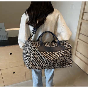 Femme élégante portant un sac de voyage à motif géométrique dans un intérieur moderne