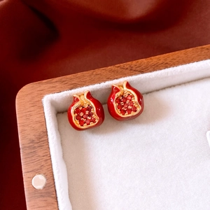 Macro shot of gold-plated pomegranate earrings with red crystals in a vintage jewelry box