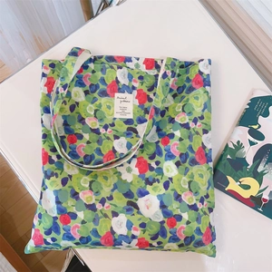 Detail view of floral cotton tote bag with brand label and artistic green pattern