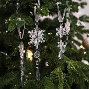 Macro shot of clear acrylic icicles and snowflakes on green pine tree branches