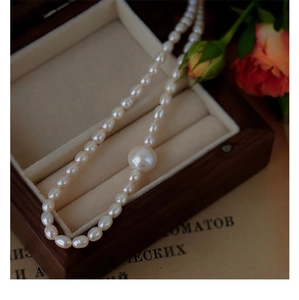 Detail of freshwater pearl necklace with round center pearl on vintage wooden box