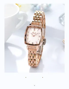 Detail of rose gold square watch dial with diamond markers and metal link strap