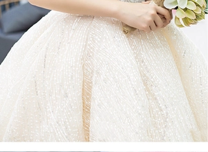 Macro shot of luxury champagne wedding dress with intricate sequins and beaded wave patterns