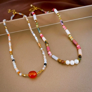 Detail of beaded necklaces with agate stones and pearls on golden metallic background