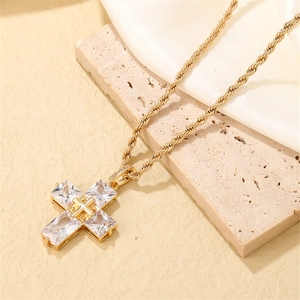 Macro shot of gold-plated cross pendant with rectangular zircon and twisted rope chain