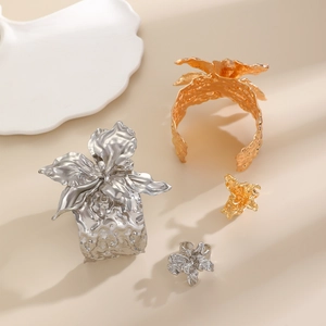 Nahaufnahme goldener und silberner unregelmäßiger Blumenarmreifen mit Skulptur-Textur
