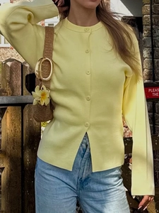 Détail d'un cardigan décontracté en tricot jaune clair avec boutons porté en extérieur