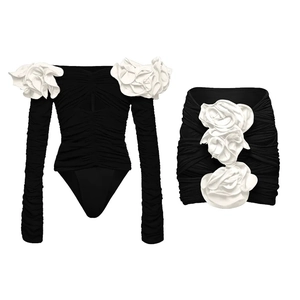 Flat lay of black swimwear with 3D white roses and delicate pleated fabric textures