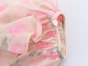 Gros plan détaillé du tissu en mousseline fleurie avec volants et un bouton blanc décoratif