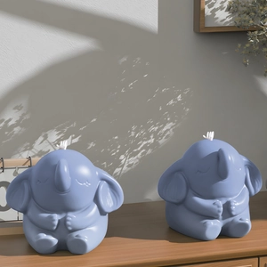 Detailed view of two light blue elephant shaped candles on a wooden surface with soft light