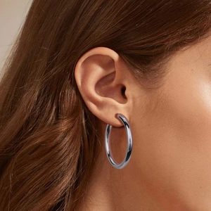 Macro shot of large polished silver S925 C-shape hoop earring on a female model