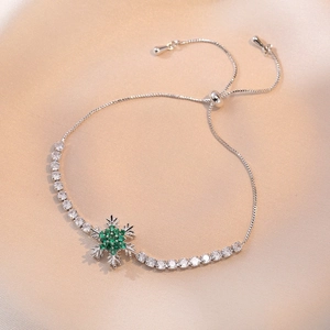Close-up of silver snowflake bracelet with green gemstone on elegant silk background