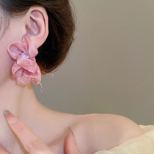 Detail of pink chiffon flower earrings with mesh petals and beaded centers worn by a model