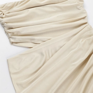 Gros plan détaillé sur le satin champagne avec textures plissées et découpes sur le côté
