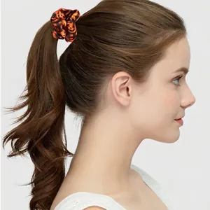 Halloween pumpkin scrunchie in bright orange satin fabric shown on high ponytail