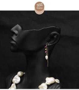 Detail of baroque pearl drop earrings with colorful beads and gold chain on black bust