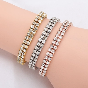 Close-up of double-row tennis bracelets in gold, silver, and rose gold on a wrist