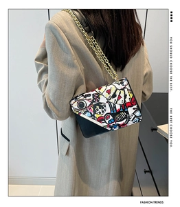 Detail of artistic graffiti patterns and gold chain strap on the crossbody square bag