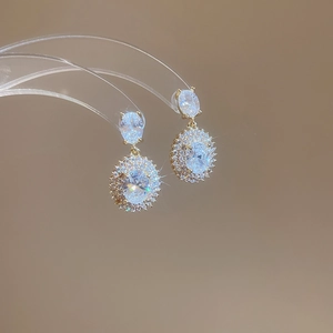 Detailed shot of gold plated oval zircon earrings hanging on a display stand