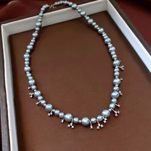 Elegant grey-blue pearl necklace featuring sparkling silver snowflake pendants on a display tray