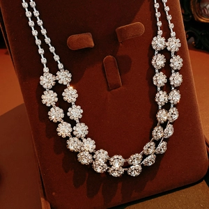 Close-up of double-layer necklace with crystal flower pendants on a brown velvet stand