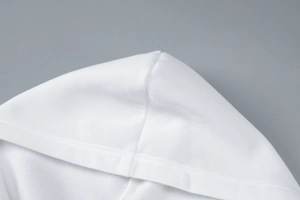Close-up of high-quality sewing craftsmanship on a white hooded knitted cardigan jacket