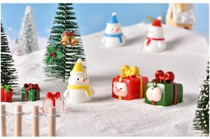 Detailed close-up of resin snowman and gift box figurines on artificial snow