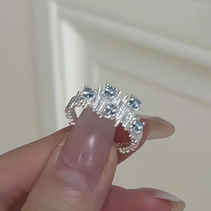 Irregular silver ring featuring clustered blue zircons worn on hand for a chic look