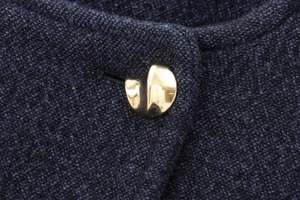 Gros plan détaillé des boutons dorés géométriques sur une veste en tweed bleu marine