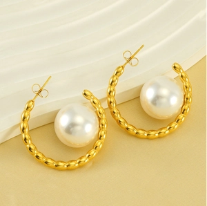 Detailed view of pearl earrings with wavy gold C-shape design and white pearls