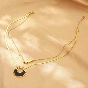 Detail of gold double-layered necklace featuring a snake chain and black fan-shaped pendant