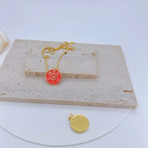 Détail d'un pendentif fleur de cerisier doré avec émail rouge et pierres scintillantes