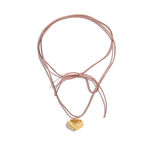 Collier avec pendentif cœur doré et cordon en daim rose pâle sur fond blanc épuré
