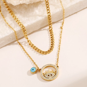 Détail d'un collier doré double couche avec pendentif œil de démon bleu sur pierre