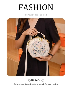 Detail of beige ethnic round bag with floral embroidery and golden metal hardware