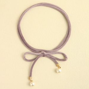 Detail of lavender velvet tie belt with gold metal ends and white pearl charms