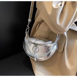 Silver crescent saddle bag with pleated texture and chain strap shown on model coat