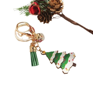 Christmas tree keychain with green tassel and sparkling sphere on festive background