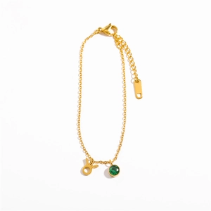 Detailed shot of golden Taurus zodiac charm bracelet with green birthstone pendant