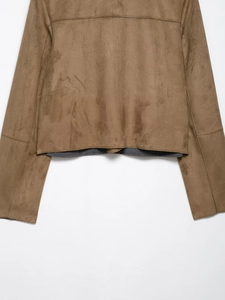 Detail view of the brown faux suede texture and sleeve seams on a short cropped jacket