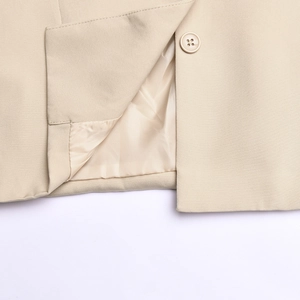 Detailed macro shot of beige cardigan hem showing smooth inner lining and matching button