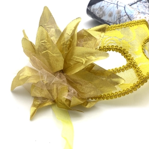 Détails d'un loup de mascarade en dentelle jaune avec textures de pétales dorés et finitions