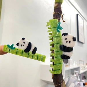 Detail of cute panda hair claw clip on a bamboo branch with vibrant green acetate material