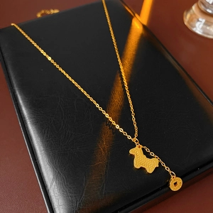 Detail view of a gold-plated necklace with dog pendant on a black leather display