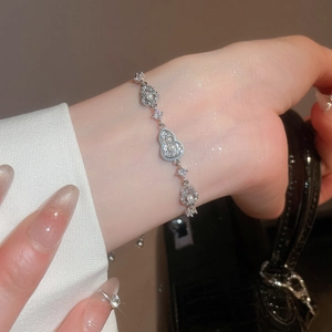 Detail of 18k gold plated bracelet featuring pearl and zircon gourd charm on wrist