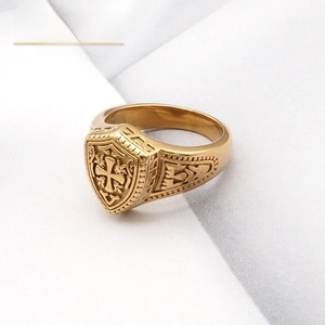 Détail d'une bague chevalière dorée avec croix en relief et gravures latérales de style rétro