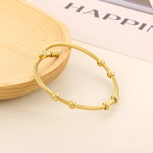 Close-up of golden cable texture adjustable bangle with sliding beads on wooden tray