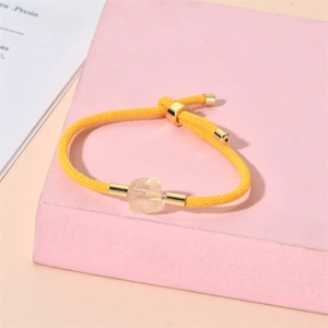 Détail du bracelet tissé jaune ajustable avec pierre brute naturelle sur support rose